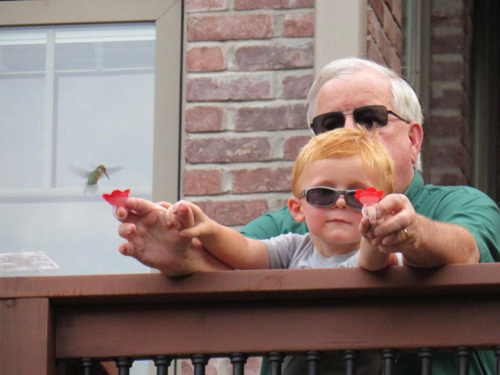 Mel Toellner with grandson, Ollie Toellner, feeding hummingbird with a HummerRing™